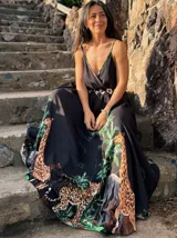 Vestido largo negro con estampado de jungla con palmeras, jirafas y leopardos. Tiene breteles finos, escote en V cruzado y cinturón con apliques brillantes.