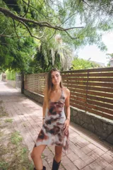 Vestido corto con estampado abstracto en tonos rosados, escote en V y breteles finos que se atan al cuello. Tiene corte en la cadera y falda con ruedo irregular y pico en lateral.