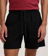 Bermuda de microfibra color beige, con cintura elástica y cordón ajustable. Presenta textura en el tejido y un bolsillo lateral.