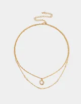 Collar corto doble dorado, con una cadena de eslabones y otra de eslabones retorcidos. La cadena más corta tiene circonitas engarzadas y la más larga tiene un dije circular con circonitas de colores.