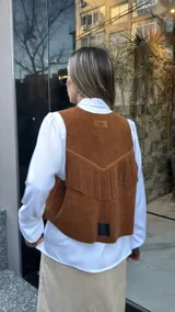 Chaleco marrón de cuero descarne con terminación en picos, tachas metálicas y flecos en la espalda.