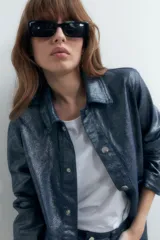 Sobrecamisa de denim metalizado color azul con cuello clásico, cierre frontal con botones, bolsillos de parche en el pecho y mangas largas.