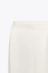 Pantalón negro de tiro alto confeccionado en tejido de punto elástico y flexible con trama compacta, mullida y opaca. Bajo acampanado.