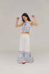 Falda larga acampanada de lino blanco con bordado floral en hilo azul en el ruedo. Presenta bolsillos laterales y cierre invisible en la espalda.