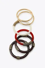 Set de cinco pulseras rígidas para mujer, que incluyen dos pulseras metálicas doradas y tres pulseras de resina en color blanco, rojo y marrón, con apliques metálicos labrados.
