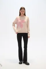 Sweater color beige con estampado de flor rosa, de corte ancho y cuello redondo.