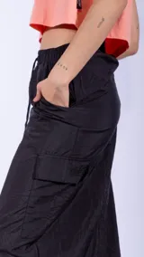 Falda midi negra de nylon con cintura elastizada ajustable con cordón, bolsillos laterales y detalle de frunces.