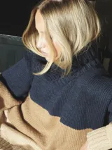 Buzo de punto grueso con bloques de color camel, azul marino y beige.