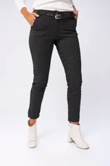 Pantalón negro con finas rayas verticales blancas, corte de vestir, bolsillos delanteros funcionales y falsos bolsillos traseros. Incluye cinturón negro con hebilla plateada.