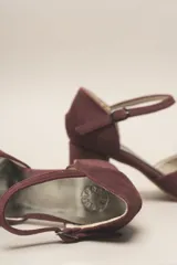 Zapato de tacón de terciopelo verde con correa al tobillo, punta redondeada y tacón cuadrado.