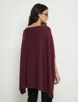 Poncho tejido de punto grueso, color mostaza/mostaza oscuro, con cuello redondo y caída amplia.