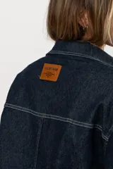 Chaqueta de jean azul oscuro con costuras blancas y lycra.