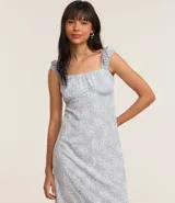 Vestido midi con estampado floral celeste y blanco, breteles anchos con volados, escote cuadrado y corte recto.