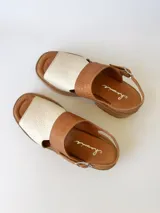 Sandalia de cuero color camel y crudo, con tira ancha sobre los dedos, tira al tobillo con hebilla y suela track.