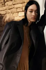 Blazer marrón de cuero sintético con solapas de muesca, cierre con tres botones, bolsillos delanteros con solapa y forro de sarga.