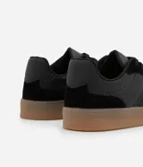 Championes urbanos de corte bajo, color blanco con detalles en gris y negro. Confeccionados en material sintético con recortes efecto gamuza y suela de látex color caramelo.