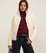 Campera puffer ultraligera color marrón, confeccionada en poliamida acolchada, con cuello alto y cierre por cremallera. Incluye bolsita con cordón.