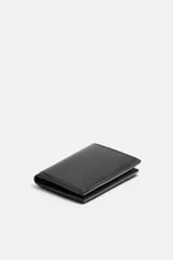 Tarjetero vertical de cuero negro con pespuntes a tono. Tiene un compartimento principal con bolsillo para billetes y tres posiciones para tarjetas en cada lado.