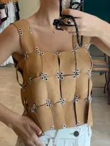 Top tipo armadura o corsé, confeccionado con tiras superpuestas de material blanco perforado (tipo puntillado) unidas entre sí mediante argollas metálicas. Presenta un diseño personalizable en color, textura y forma (Halter, Cuello cuadrado o Cuello en V).