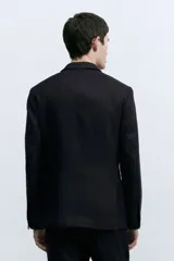 Blazer negro de lino liviano con solapas de muesca finas y ojal decorativo. Modelo de botonadura sencilla con bolsillo superior, bolsillos delanteros con solapa y dos bolsillos en el interior. Cierre de dos botones, botones decorativos en los puños y abertura doble atrás. Corte ajustado que realza el contorno del cuerpo creando una silueta entallada. Forrado.