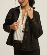 Campera trucker de jeans negro con efecto tintado, cuello clásico, cierre frontal con botones, solapas en el pecho con botones y corte holgado.