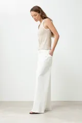 Pantalón de jean blanco, tiro alto, de corte ancho (wide leg) y largo.