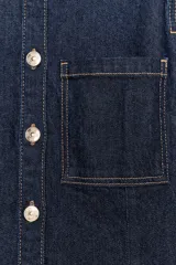 Camisa de denim color azul oscuro, de manga larga y corte entallado. Presenta cuello solapa, un bolsillo de plastrón en el pecho y cierre frontal con botones dorados.
