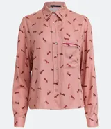 Camisa de viscosa color rosa con estampado de caballos en marrón. Tiene cuello camisero, cierre con botones, mangas largas, un bolsillo frontal y detalle de vivo contrastante.