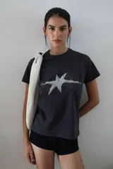 Remera negra de algodón con cuello redondo y manga corta. Estampa frontal con diseño de estrella blanca con líneas finas.
