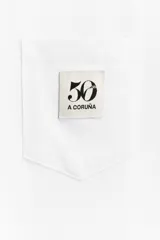 Camiseta negra de algodón con cuello redondo y manga corta. Tiene un bolsillo de parche en el pecho con el logo del 50 aniversario.