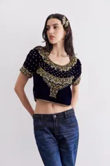 Top corto de terciopelo azul marino con escote redondo y mangas cortas. Presenta apliques bordados en hilo de lurex dorado, piedras y mostacillas.