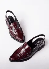 Mocasines color borgoña de cuero con punta fina, detalle de apliques metálicos y tira trasera con hebilla.