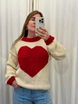 Sweater tejido a mano en Uruguay, color crema con un corazón rojo en el frente y puños y cuello acanalados en rojo. Confeccionado en 100% lana merino.