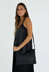 Bandolera negra de cuero trenzado con correa larga al hombro.