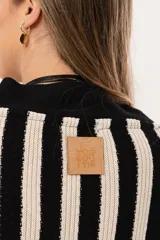 Saco oversize tejido a rayas verticales en blanco y negro, con escote en V y botones.