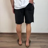 Short negro de algodón rústico con corte amplio y ruedo desflecado.