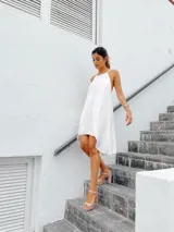 Vestido corto blanco con escote halter y espalda descubierta con tiras ajustables.