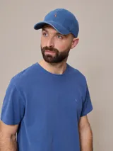 Gorro de jean azul con visera y logo bordado en naranja.