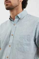 Camisa celeste de manga corta con cuello abotonado y bolsillo en el pecho.