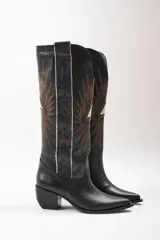 Botas texanas de cuero color marrón con bordados de estrellas y rayos de sol en color blanco. Tiene un pequeño taco de madera y detalles en rojo en el borde superior.