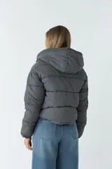 Campera puffer corta color negro con capucha, cierre metálico y botones a presión. Cuenta con bolsillos laterales invisibles con cierre.