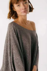 Blusa beige de tejido brillante, con cuello bote y mangas murciélago.