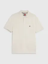 Chomba color crema de piqué de algodón, corte regular, cuello de chomba y cartera de dos botones. Tiene el logo de Tommy Hilfiger bordado en el pecho.
