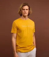 Remera de hombre color mostaza, de corte comfort, con cuello redondo y manga corta. Estampa frontal con la frase "La confiance est le secret du succès" en color blanco.