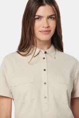 Camisa de lino color beige, de manga corta, con medio botón, dos bolsillos en el pecho y botones metálicos personalizados.