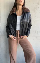 Campera negra de cuero sintético, con cuello de piel sintética con estampado animal print, cierre frontal con botones a presión, bolsillos con solapa en el pecho y corte recto.