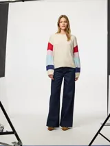 Sweater de punto color crema con cuello redondo y mangas largas con rayas horizontales en colores rojo, celeste, azul y rosa.