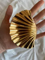 Pinza para el pelo dorada con forma de concha de mar.