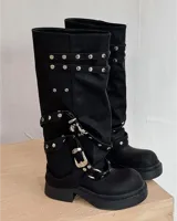 Botas negras de caña alta con hebillas y taco bajo.