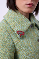 Campera corta de poliéster texturizado color verde oscuro, con cuello camisero, cierre frontal con botones a presión, bolsillos delanteros y forro interior. Incluye pins decorativos.